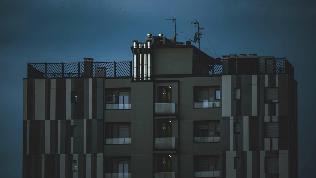 A modern high-rise residential building under a moody dusk sky.